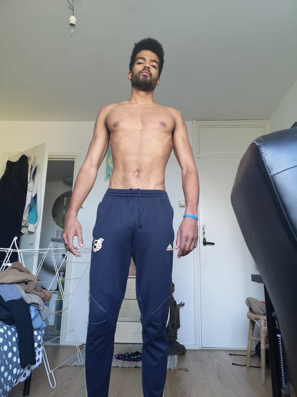 Manu at home, standing in a tracksuit, very skinny again