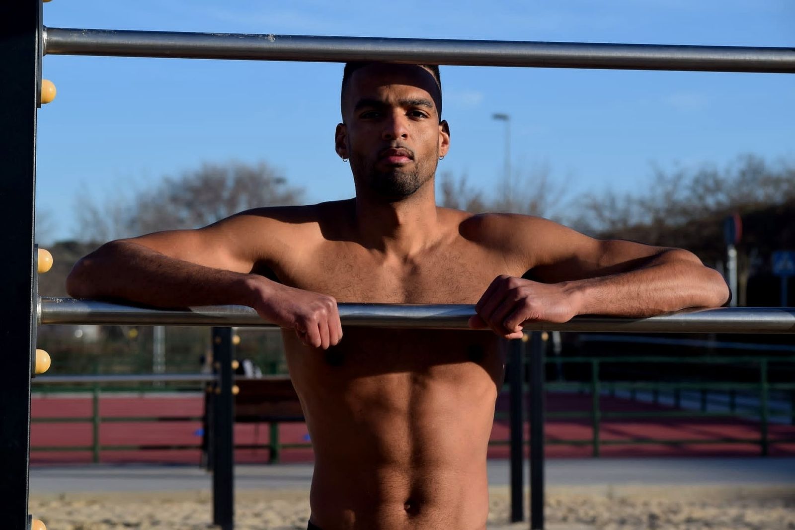 Manu today, holding himself up on outdoor calisthenics bars in the late-afternoon light
